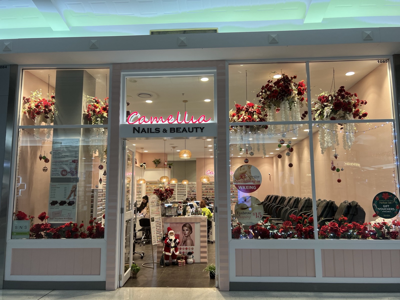 Camellia Nails & Beauty storefront at night, festively decorated